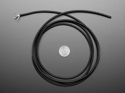 Top Down Shot of the Slim Cable - 1820mm / 6 feet long coiled up next to a U.S. Quarter for Scale.