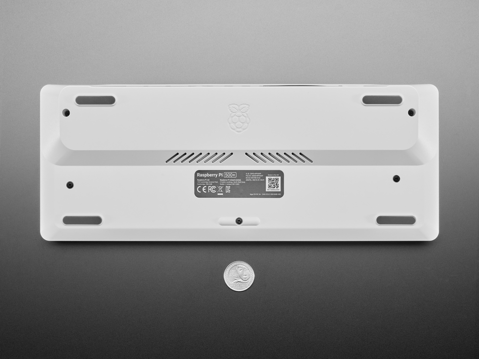 Top Down Bottom Shot of the Raspberry Pi 500+ next to a U.S. Quarter for Scale.