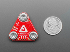Red, triangle-shaped muscle sensor breakout with U.S. quarter for scale.