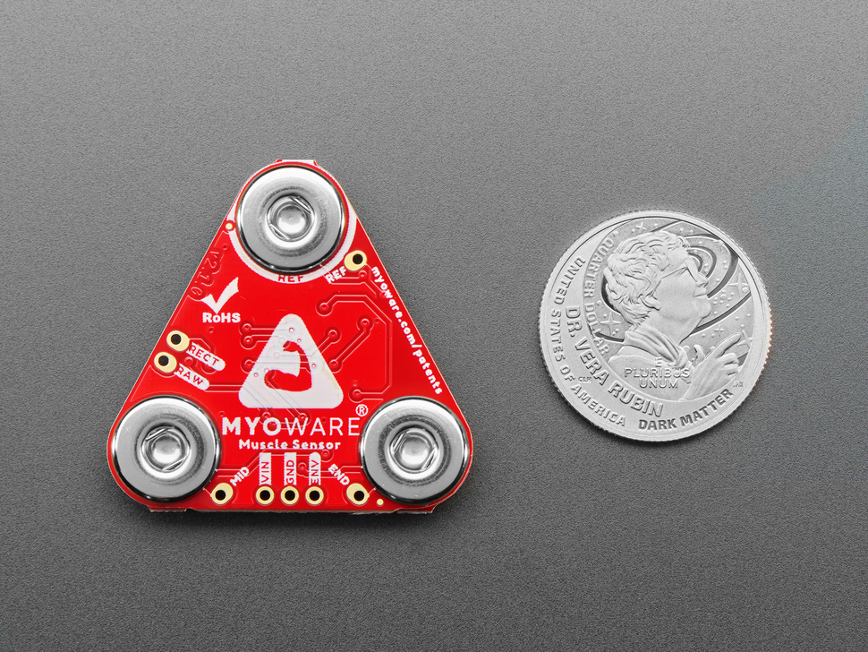 Red, triangle-shaped muscle sensor breakout with U.S. quarter for scale.
