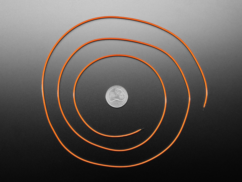 Long, orange LED filament coiled around a U.S. quarter for scale.