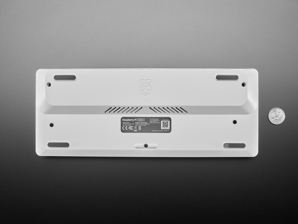 Top Down Bottom Shot of the Raspberry Pi 500+ Keyboard next to a U.S. Quarter for Scale.