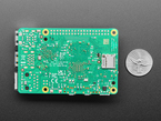 Back of green credit-card-sized microcontroller with U.S. quarter for scale.
