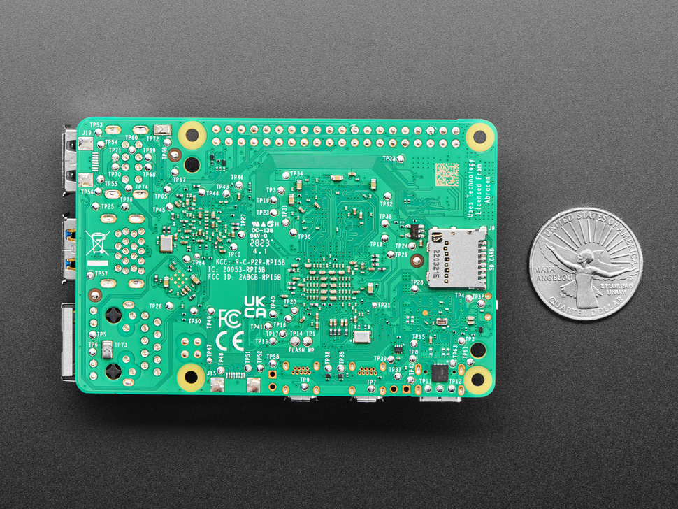 Back of green credit-card-sized microcontroller with U.S. quarter for scale.