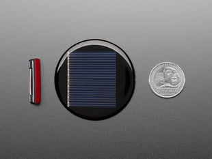 Round solar panel enamel pin next to lapel pin and US quarter for scale.