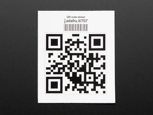Square sticker with a QR code in black on a white background, with black trimming. Mounted on white paper with barcode. 