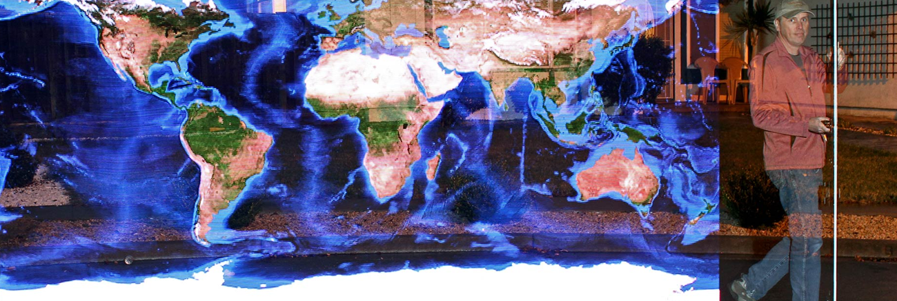 Man holding a light painting stick, and a light painted image of the world is shown